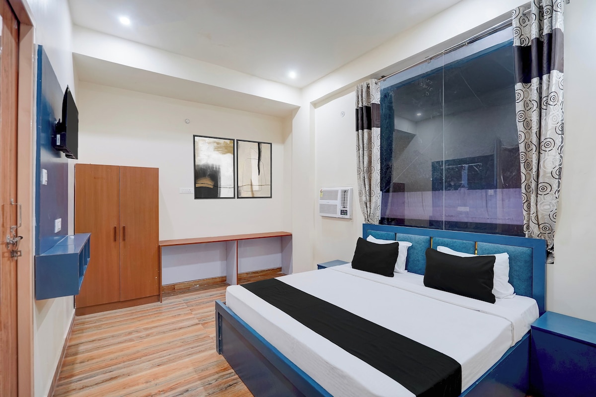 Un dormitorio con cama, armario, escritorio y ventana con cortinas.