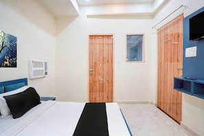 Ein Schlafzimmer mit einem Bett, einer Wand-Klimaanlage, einem Gemälde und einem Fernseher auf einem Schrank.