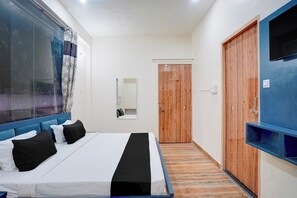 Habitación de hotel con una cama, un armario de madera, un espejo y un televisor.
