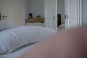 Ein Schlafzimmer mit einem Bett, einem Schminktisch und einer Tür zu einem weiteren Raum.