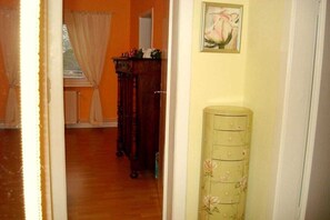 A hallway with a wooden floor, a green cabinet with drawers, and a painting on the wall. - Bella Rosa **** Lüneburg (Lüneburg)