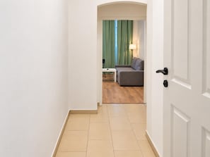 A hotel corridor leading to a room with a sofa, a small table, and a lamp. - Palace Days and Concert Nights 2BR near Westbahnhof (Vienna)