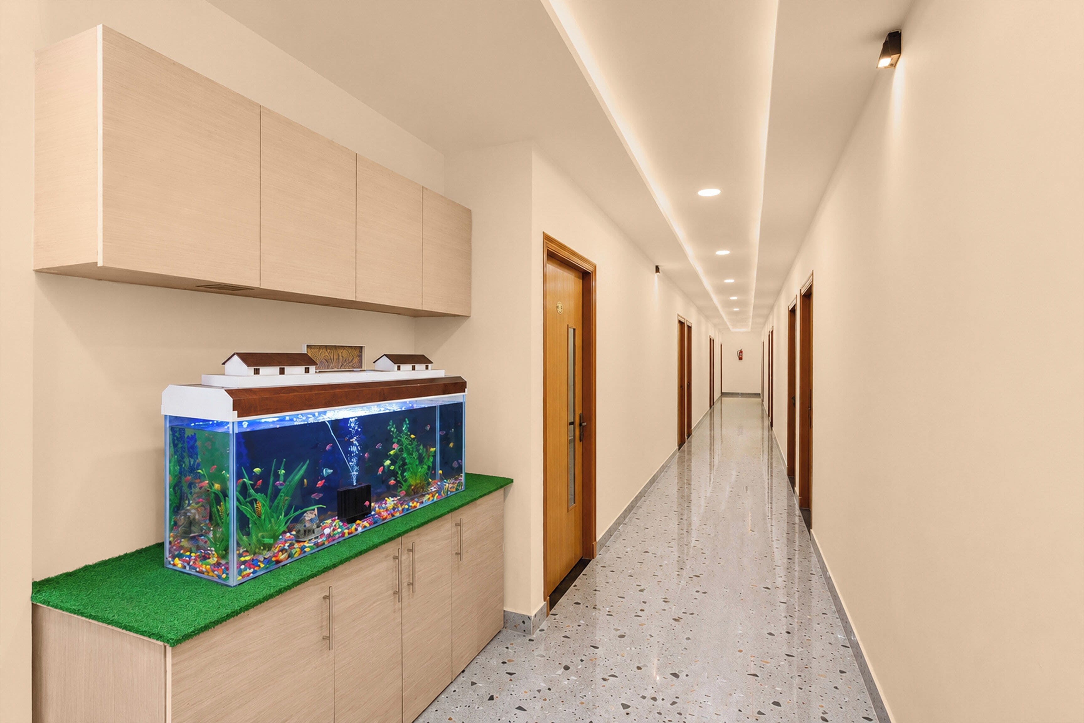 Un couloir avec un long passage, des armoires en bois, un aquarium et une porte.