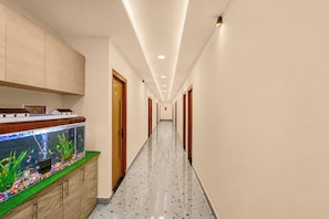 A hallway with a fish tank, wooden cabinets, and a speckled floor. - Hotel O A One hotel 2 and Banquet (Lucknow)
