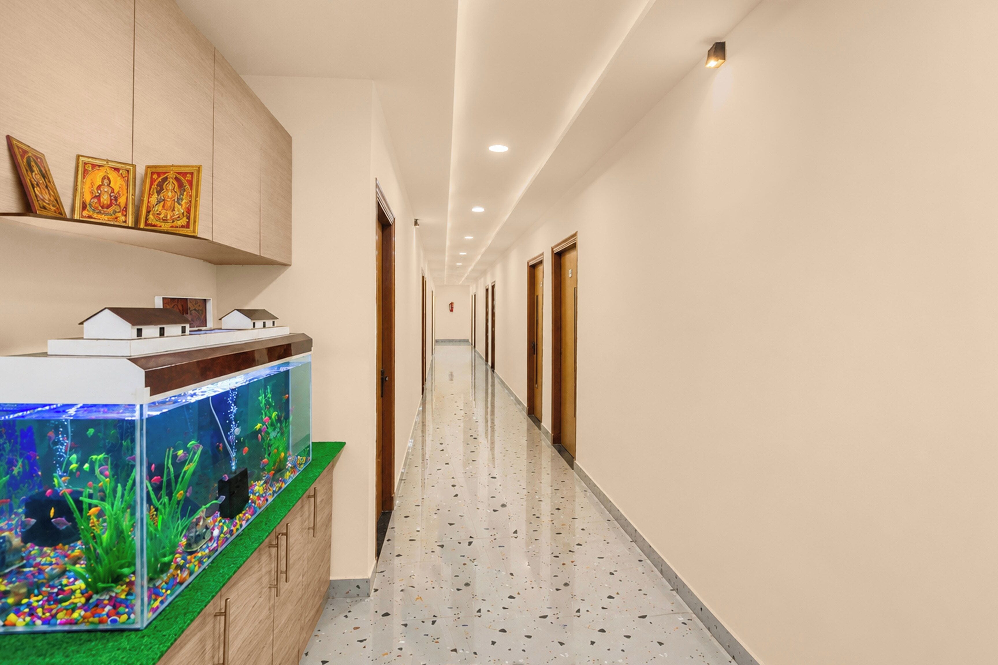 A hotel corridor with a fish tank, wooden cabinets, and doors.