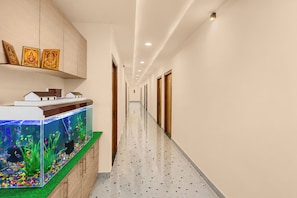 Corredor de hotel com aquário, armários de madeira e portas.