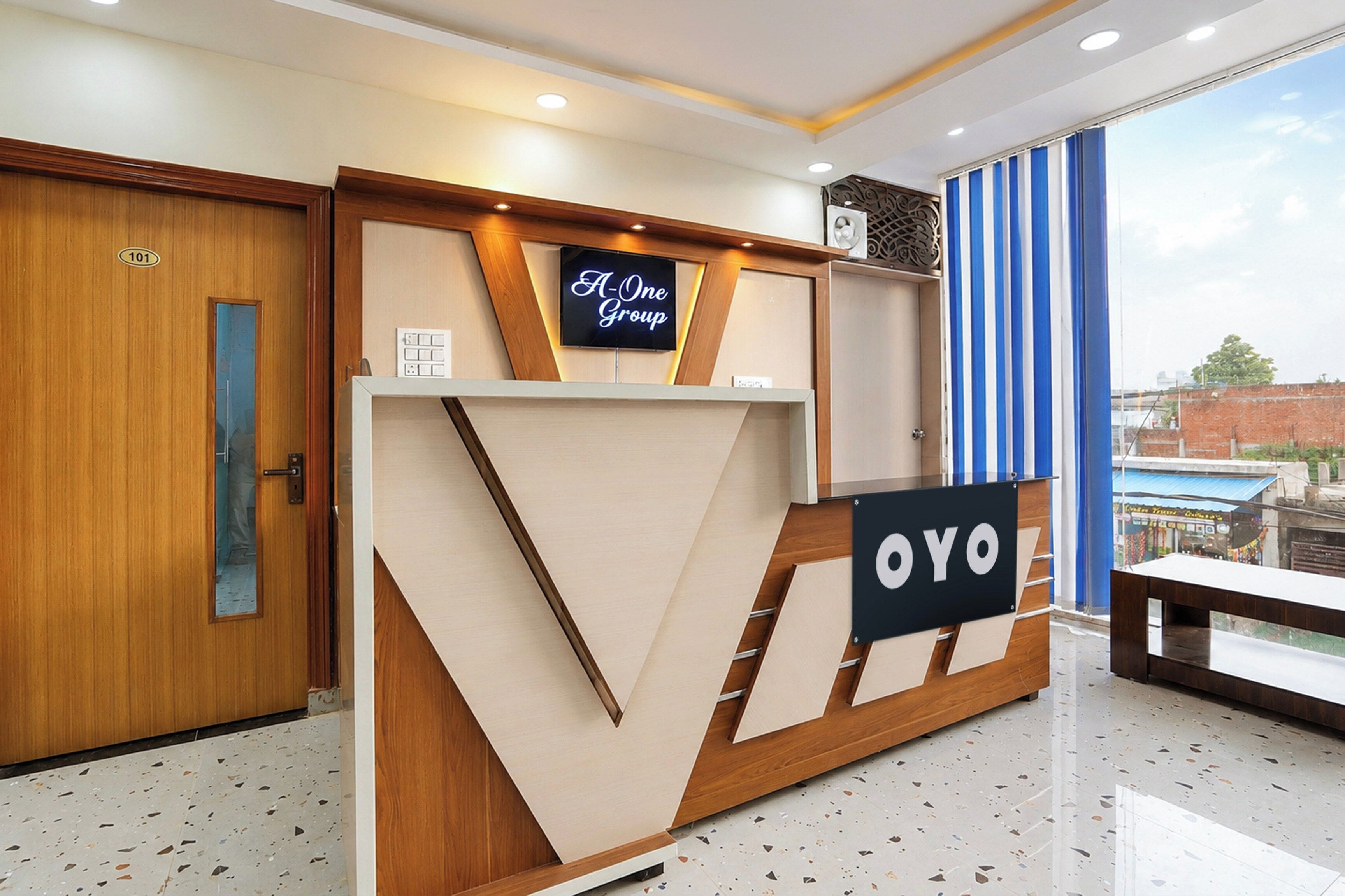 Un comptoir d’accueil avec une enseigne indiquant « A-One Group » et « OYO ».