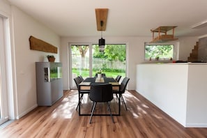 A modern kitchen with a dining area, wooden flooring, and a view of the outdoors. - Holiday home South Harz (Neustadt\/Harz)
