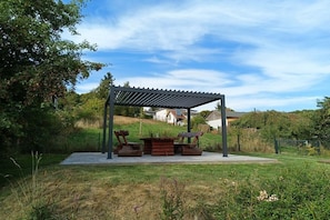 An outdoor patio area with a pergola structure, a fire pit, and a seating arrangement. - Holiday home South Harz (Neustadt\/Harz)
