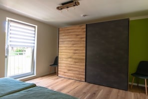 A room with a sliding door, a bed, a chair, and a window with blinds. - Holiday home South Harz (Neustadt\/Harz)