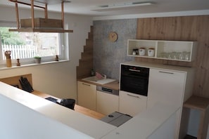 A compact kitchen with a built-in oven, a sink, and a clock on the wall. - Holiday home South Harz (Neustadt\/Harz)