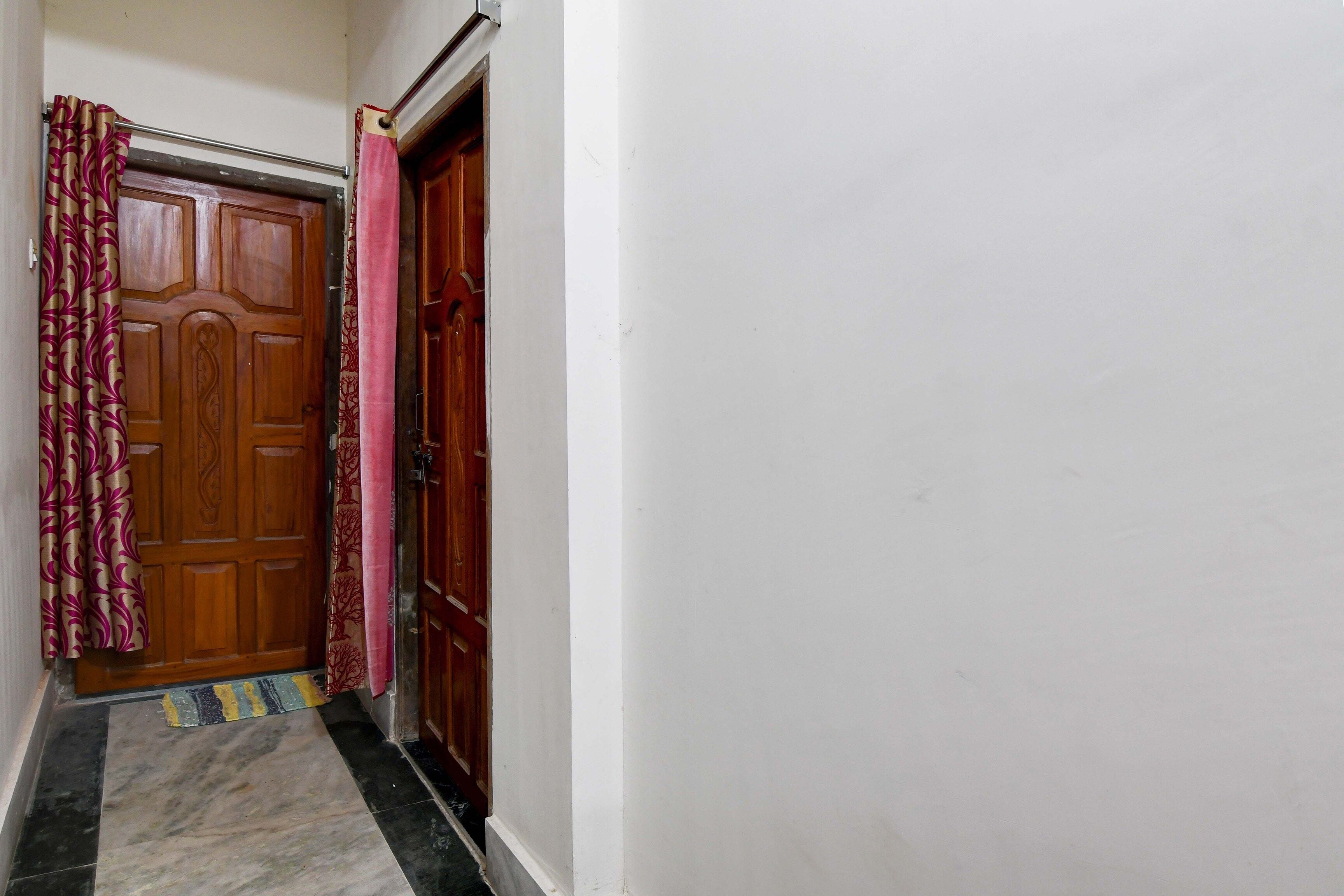 A hallway with a wooden door, a metal handrail, and a patterned curtain.