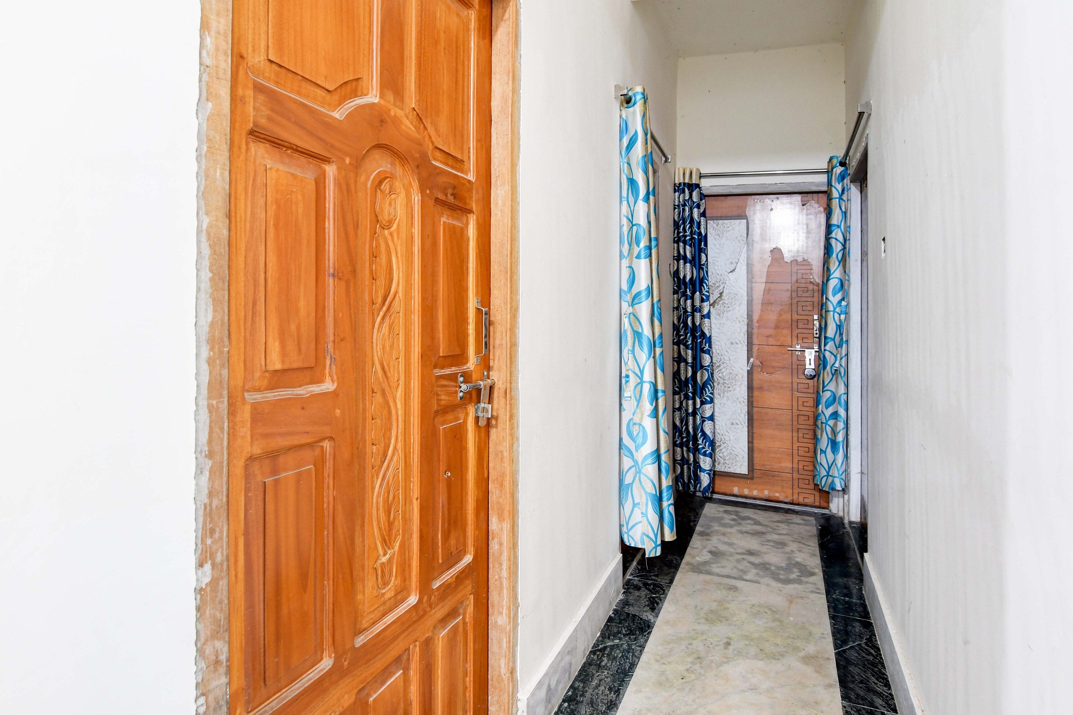 Un pasillo con una puerta de madera y cortinas estampadas.