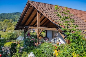 A traditional wooden chalet with a sloped roof, surrounded by a lush garden with various plants and flowers. - Holiday apartment with 1 bedroom (Oberkirch-Bottenau)