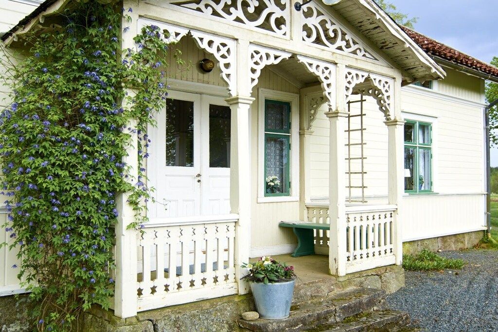A white building with a porch, a door, and a window.
