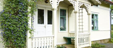 A white building with a porch, a door, and a window.