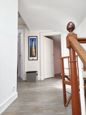 Ein Flur mit einer Holztreppe, einer Tür zu einem anderen Raum und einem gerahmten Bild an der Wand.