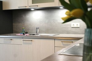 Eine moderne Küche mit einer Edelstahlspüle, einem Wasserhahn und einer Arbeitsplatte mit einer Flasche und einem Schwamm.