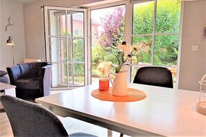 A modern dining area with a table, chairs, and a window with a view of greenery. - Holiday apartment with 2 bedrooms (Schönhagen)