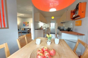 A dining area with a table set for two, a bowl of apples, and a potted plant. - Holiday home in Geel with swimming pool (Geel)