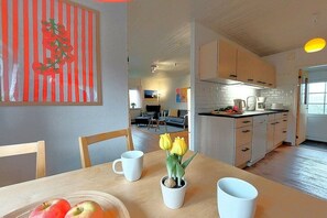 Una cuina moderna amb armaris blancs, una taula de dinar amb un ram de flors i una cesta de fruita.