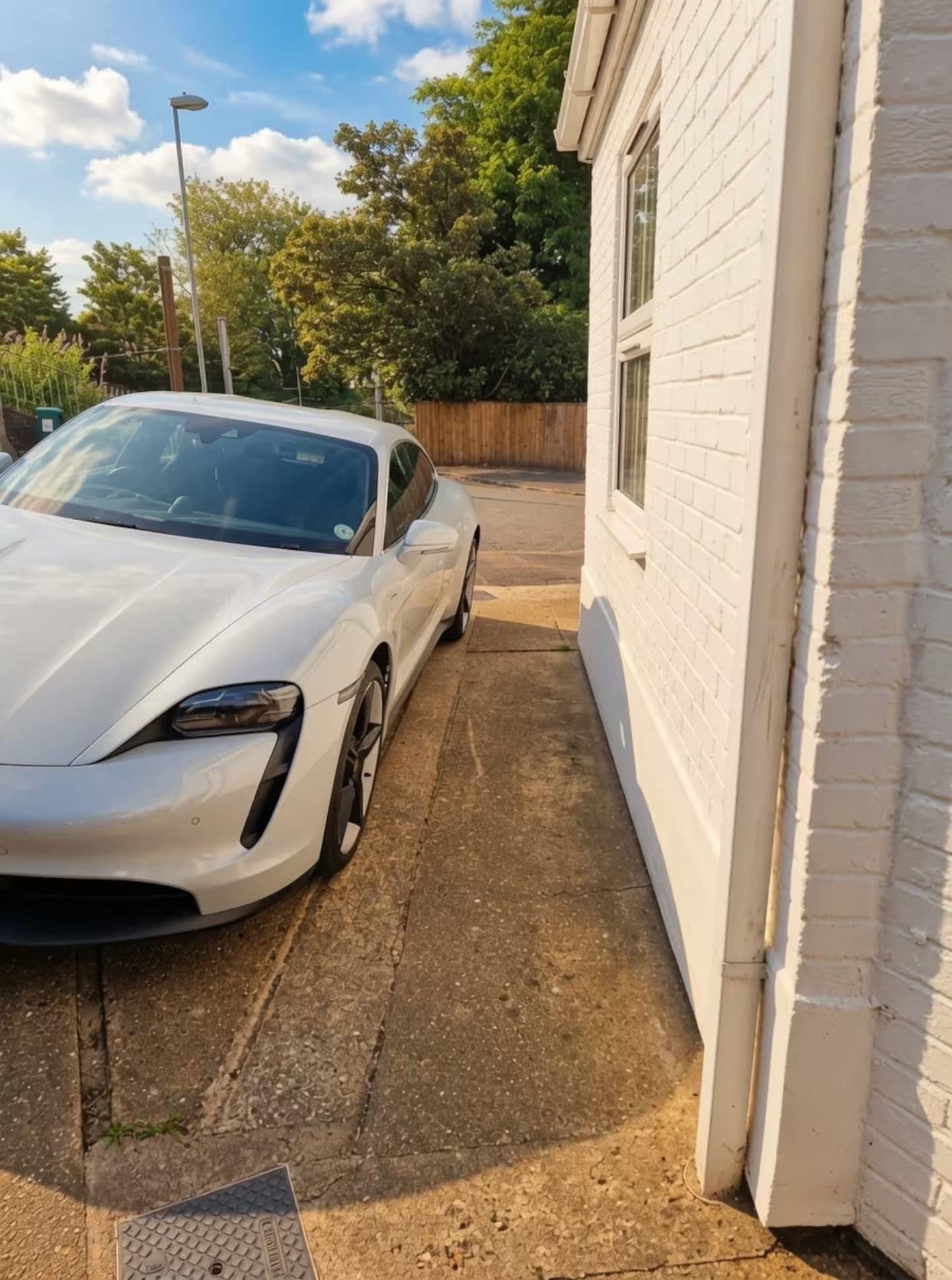 A white sports car parked in a driveway next to a white building.