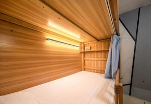 A wooden bunk bed with a headboard, a bedside table, and a wall-mounted shelf. - YangShuo Backpacker Hostel  (Guilin)