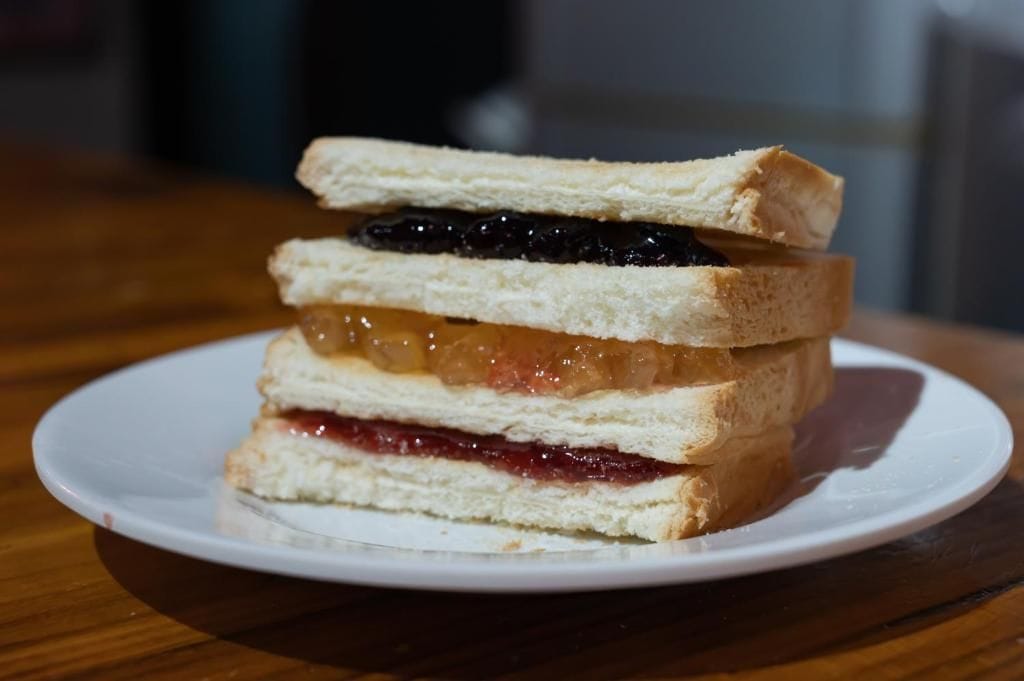 A sandwich with multiple layers of bread and fillings on a white plate.