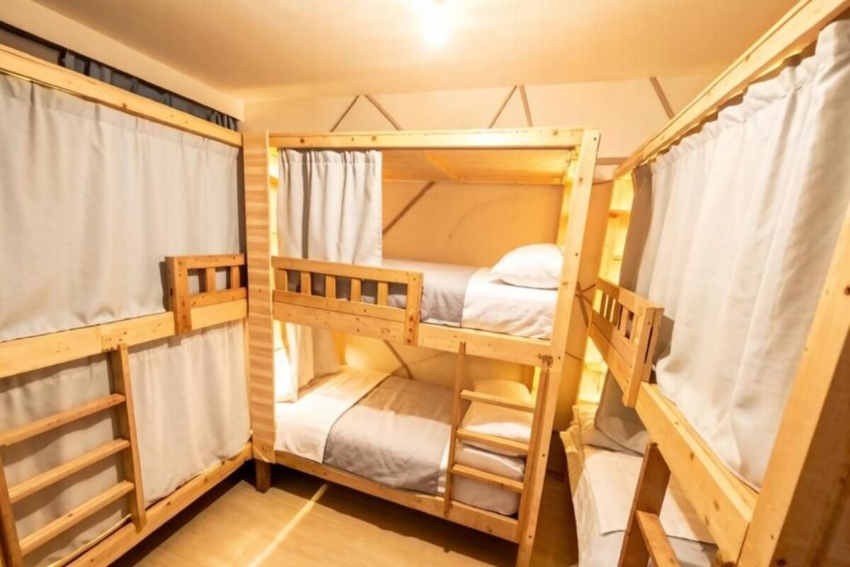 Dormitorio con literas de madera, cortinas y una lámpara.