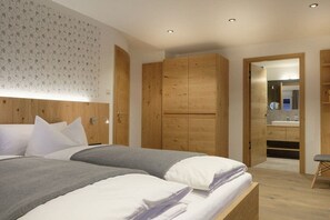 A bedroom with a bed, wooden wardrobe, and a bathroom visible through an open door. - Heimat1883 - Coachman (Garmisch-Partenkirchen)