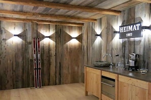A wooden interior with a sign reading 'HEIMAT 1883,' a wooden cabinet, and skis leaning against the wall. - Heimat1883 - Coachman (Garmisch-Partenkirchen)