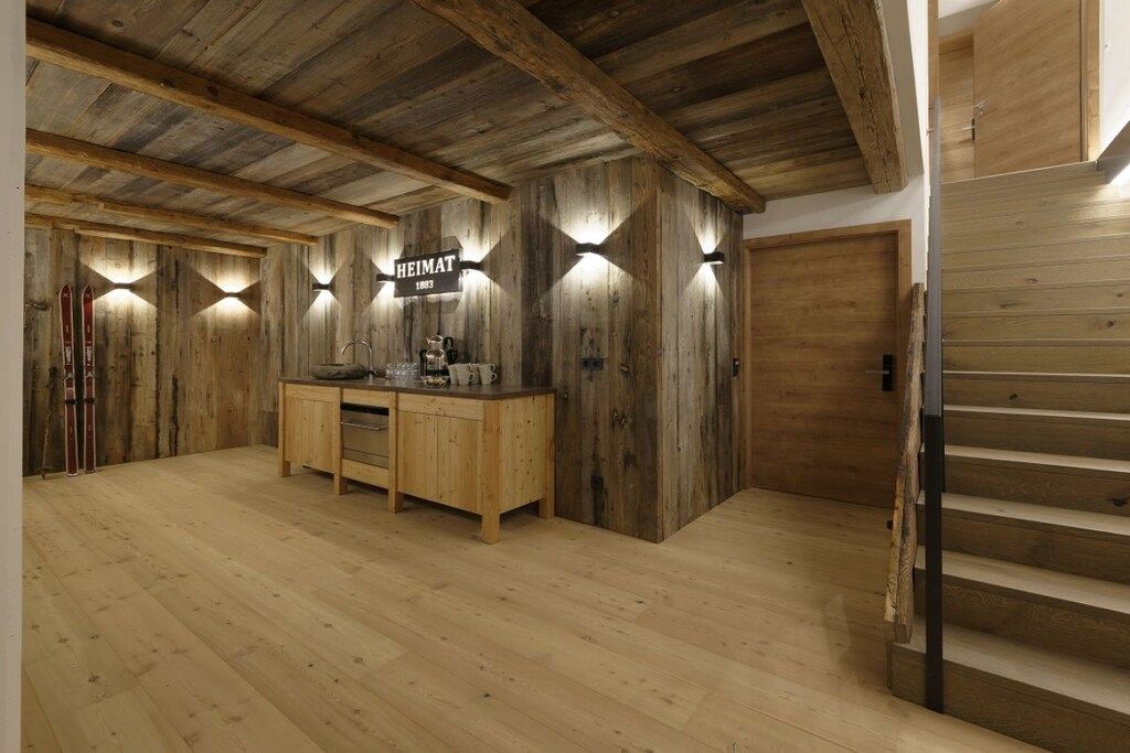 A wooden interior with a wooden staircase, a wooden cabinet with a sign, and a ski rack.