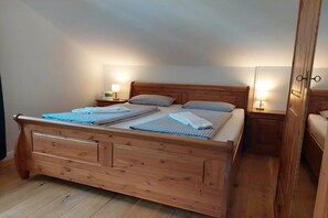 A wooden bed with a headboard, two bedside tables with lamps, and a wooden floor. - Holiday apartment Spitzenblick (Garmisch-Partenklirchen)