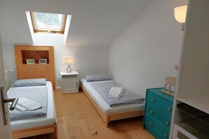 A small, compact room with two beds, a skylight, a small desk, and a dresser. - Holiday apartment Spitzenblick (Garmisch-Partenklirchen)
