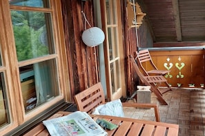 A wooden deck with a table, chairs, and a hanging lantern. - Holiday apartment Spitzenblick (Garmisch-Partenklirchen)
