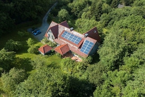 Een huis met zonnepanelen, omgeven door een dicht bos.