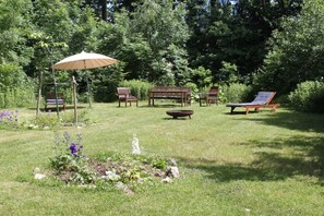 A garden with a swing set, a bench, a lounge chair, and a fire pit. - Goldberg Forest Lodge (Bad Harzburg)