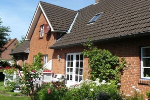 A brick house with a tiled roof, a white door, and a small window. - Holiday apartment with 1 bedroom (Rendsburg)