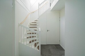 A white staircase with a wooden handrail leading to a closed door. - Holiday Home in Uitdam near Markermeer (Uitdam)