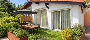 A modern outdoor dining area with a table and chairs, a grill, and a patio umbrella. - New Listing (Soustons)