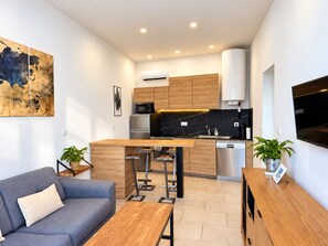 A modern kitchen with a central island, a grey sofa, and a wooden dining table. - New Listing (Soustons)
