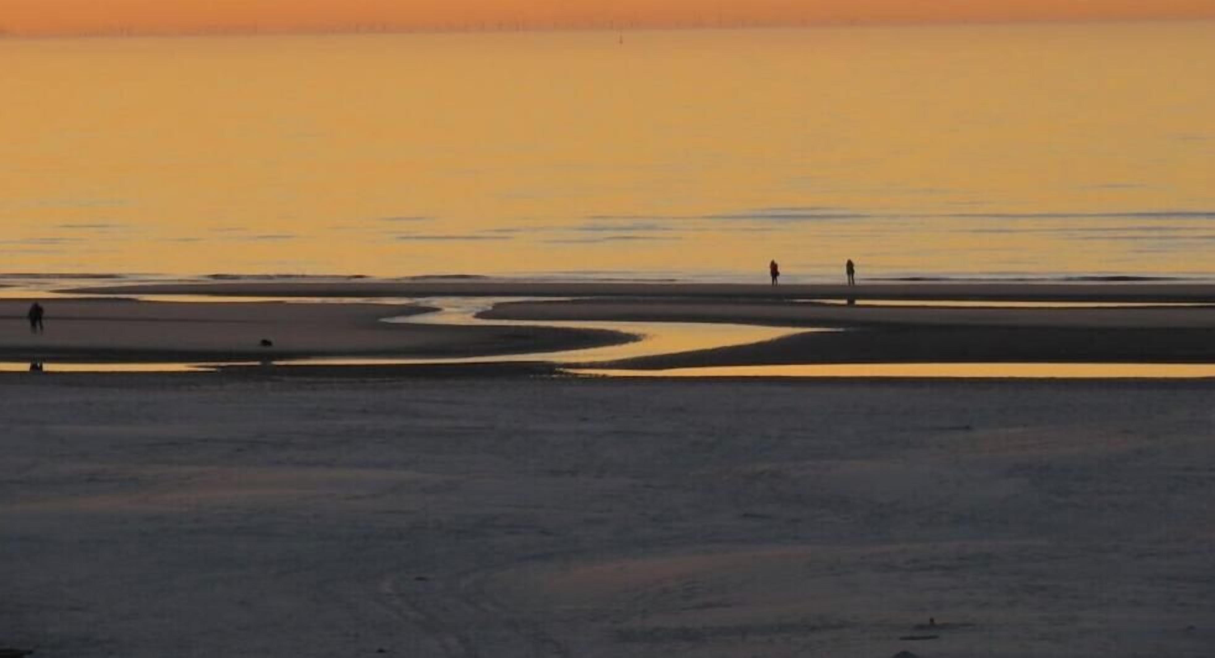 A beach scene with a calm sea and a sunset.