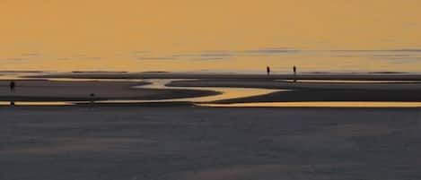 A beach scene with a calm sea and a sunset.