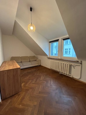 A loft bedroom with a herringbone wooden floor, a sofa, a wooden cabinet, and a pendant light. - Lumina 2BR Apt in the Center I 8 guests (Warszawa)