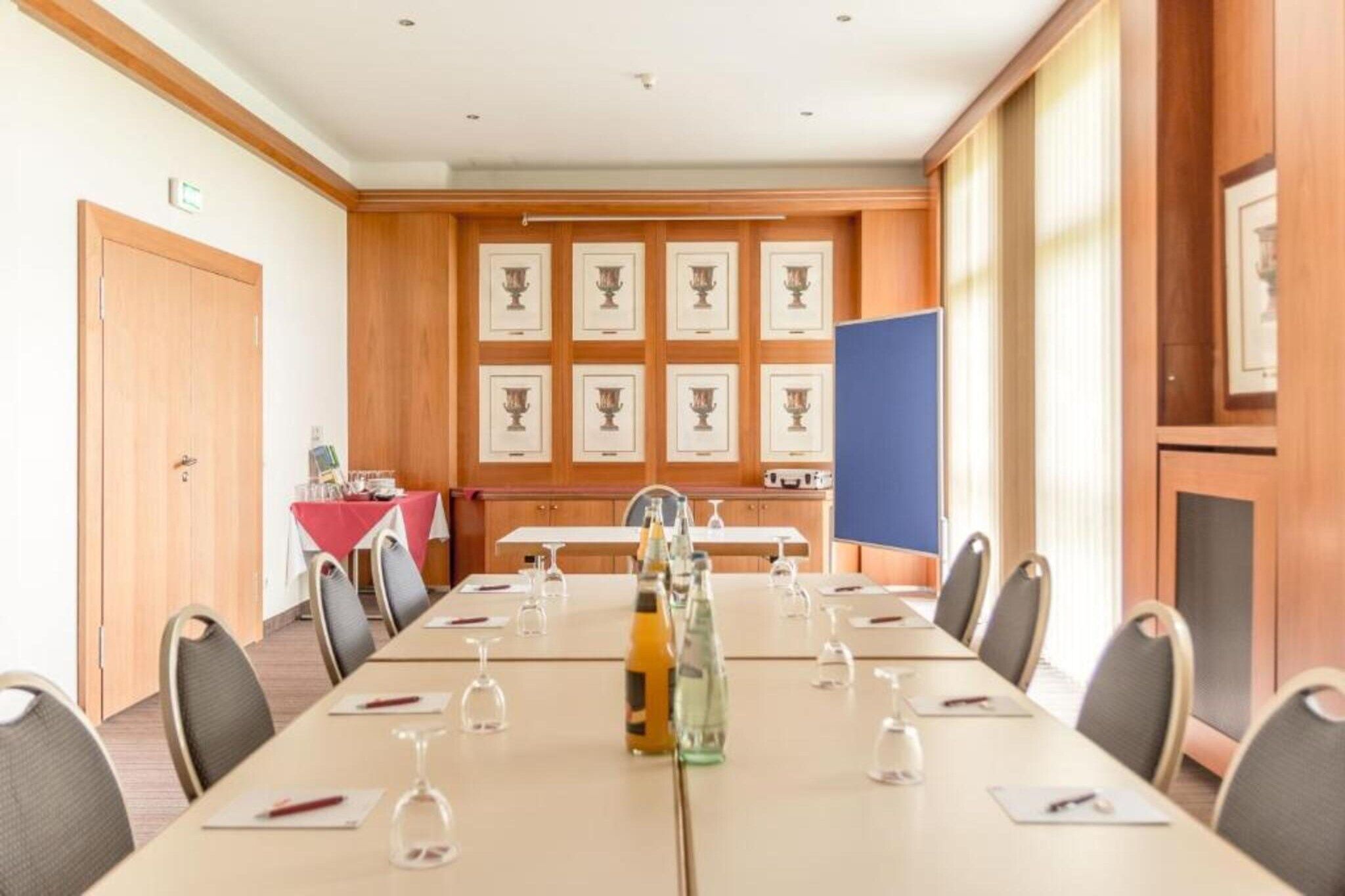 Een vergaderruimte met een lange tafel, stoelen en ingelijste foto's aan de muur.