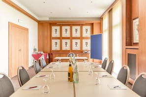 Un salón de conferencias con una mesa larga, sillas y cuadros en la pared.