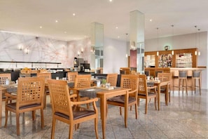 Un restaurant avec des chaises et des tables en bois, un coin bar et un décor intérieur moderne.