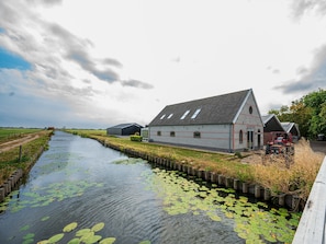 Ländliche Landschaft mit Kanal, Backsteingebäude und Traktor in Rot.
