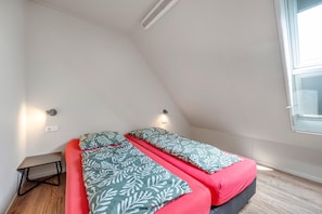 Ein Zimmer mit zwei Betten, einem kleinen Tisch und einem Fenster.