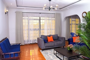 Ein Wohnzimmer mit grauem Sofa, blauem Sessel und Couchtisch.